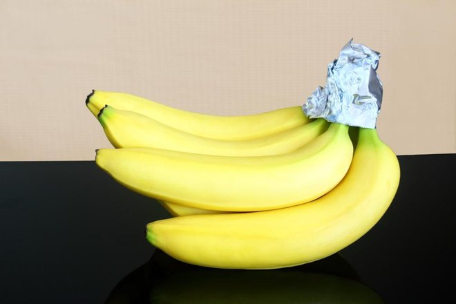 Nekateri obstojnost bananam podaljšajo tako, da njihove peclje ovijejo v folijo. To naj bi upočasnilo njihovo zorenje. Foto: Shutterstock