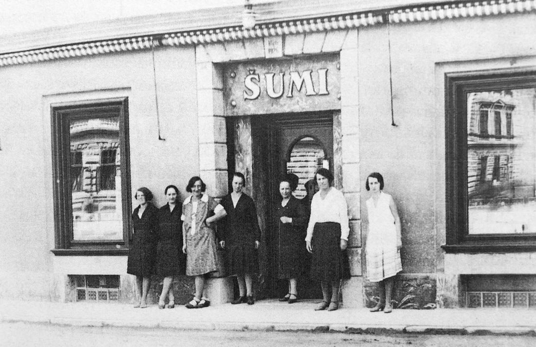Prodajalke pred trgovino Šumi okrog leta 1930. Fotografija je last Angelike Hribar, vnukinje Evgenije Šumi.